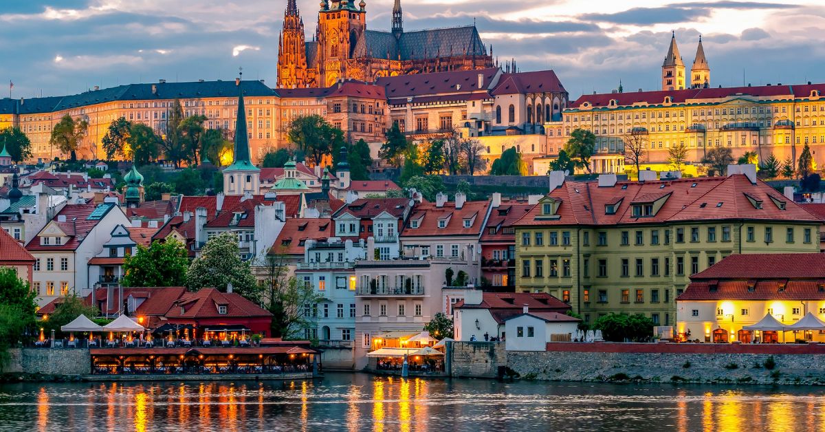 Castelul din Praga și Mala Strana luminate seara, văzute de pe Vltava