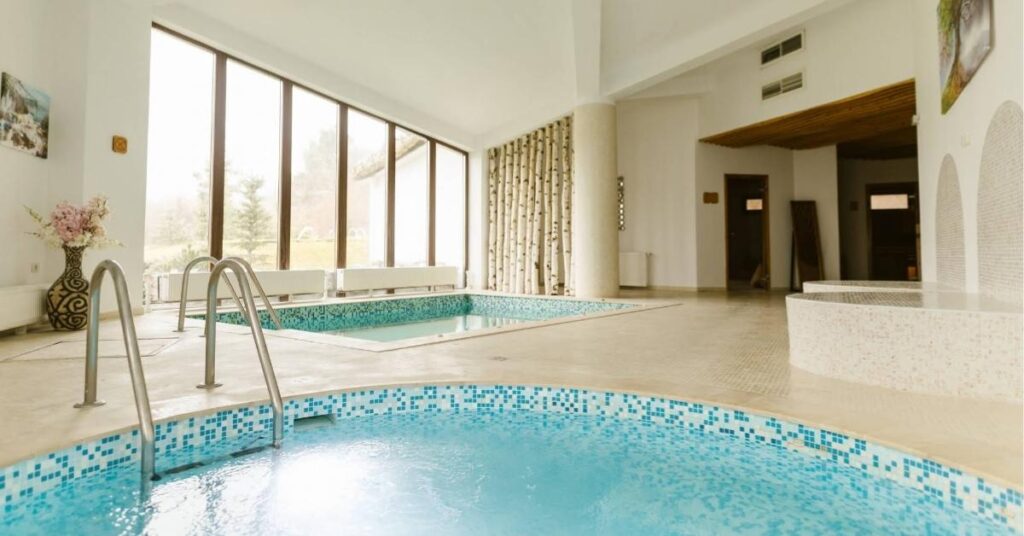 Bazinele interioare cu apă caldă din spa-ul Wolkendorf Bio Hotel, cu ferestre mari spre grădină