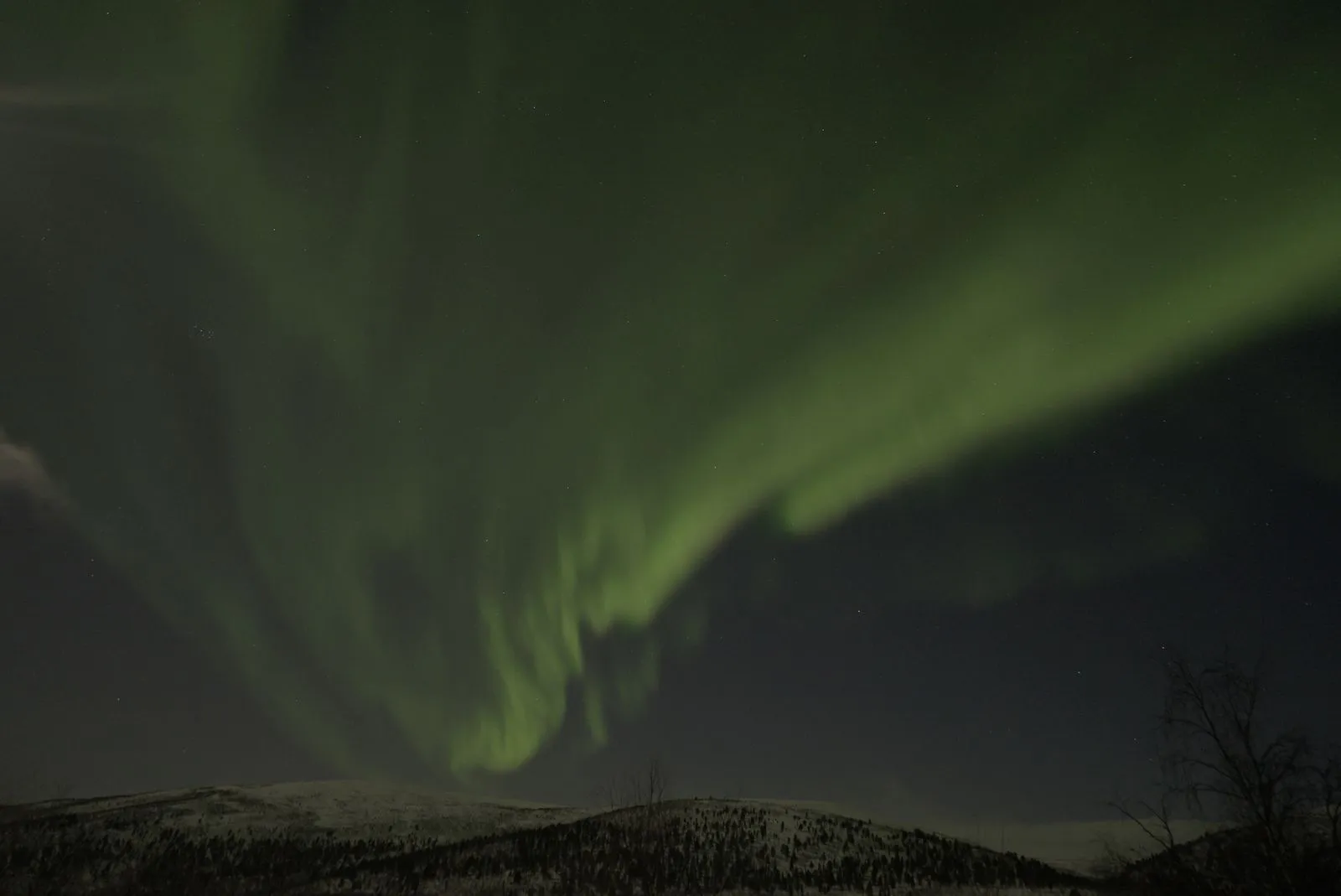 Aurora în arc deasupra dealurilor de la Utsjoki, în nordul Finlandei