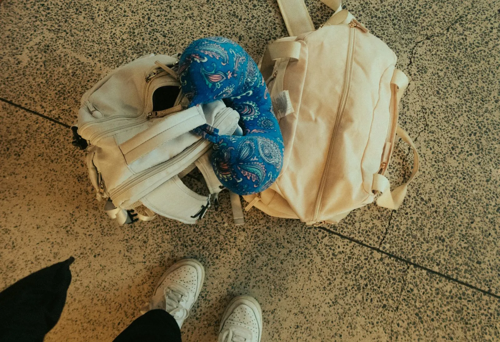 Două rucsacuri mici și o pernă de gât pe podeaua unui aeroport, bagaj de mână pentru zbor low-cost