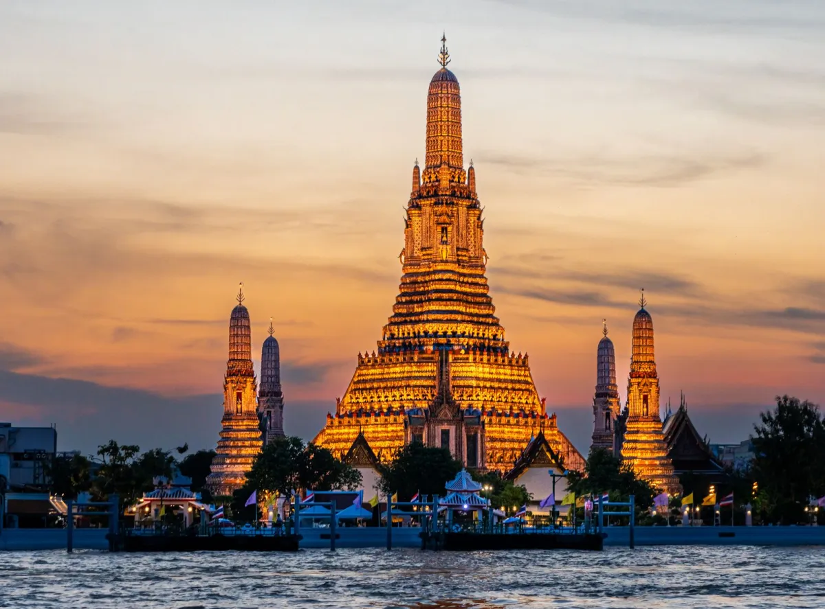 Templul Wat Arun iluminat la apus, pe malul râului Chao Phraya din Bangkok