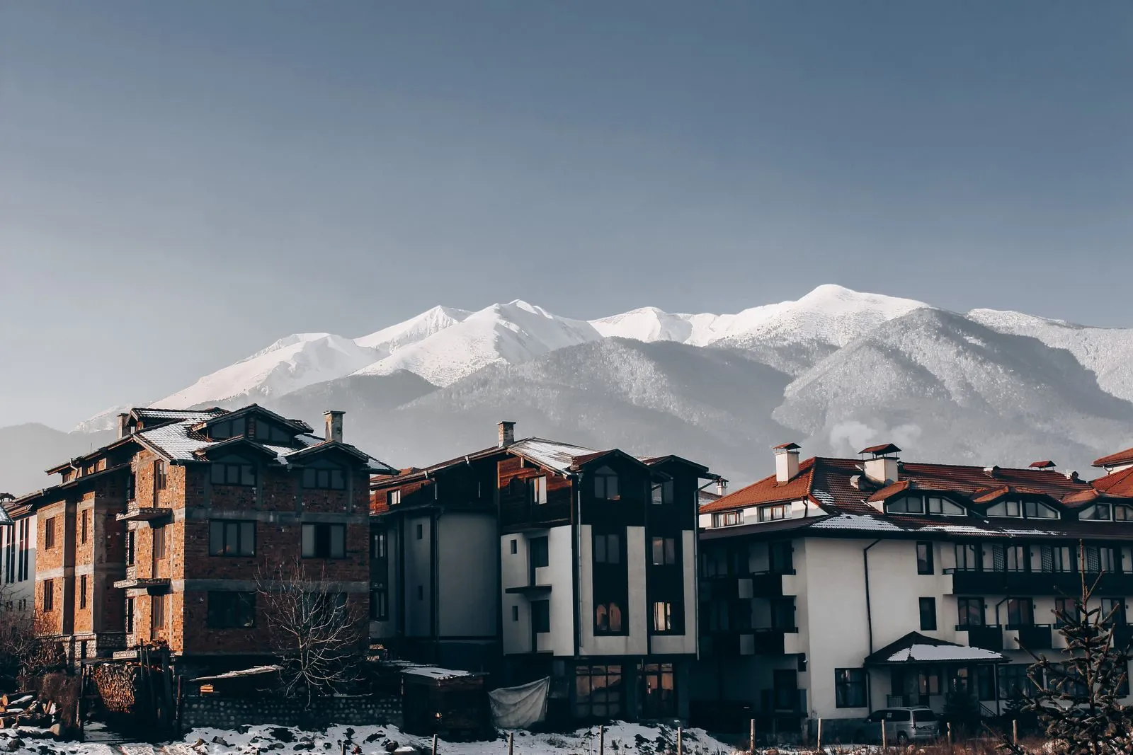 Case din Bansko acoperite de zăpadă, cu vârfurile Munților Pirin în fundal