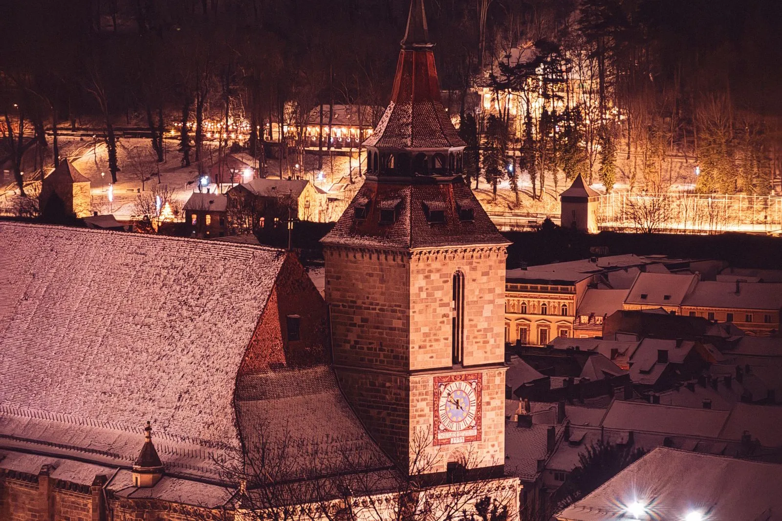 Biserica Neagră și centrul vechi al Brașovului noaptea, iarna, cu acoperișuri acoperite de zăpadă