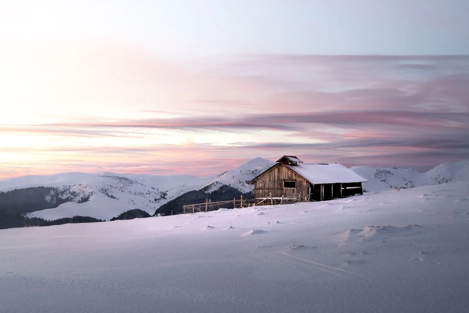 Cabană de lemn pe un munte înzăpezit din România, la apus