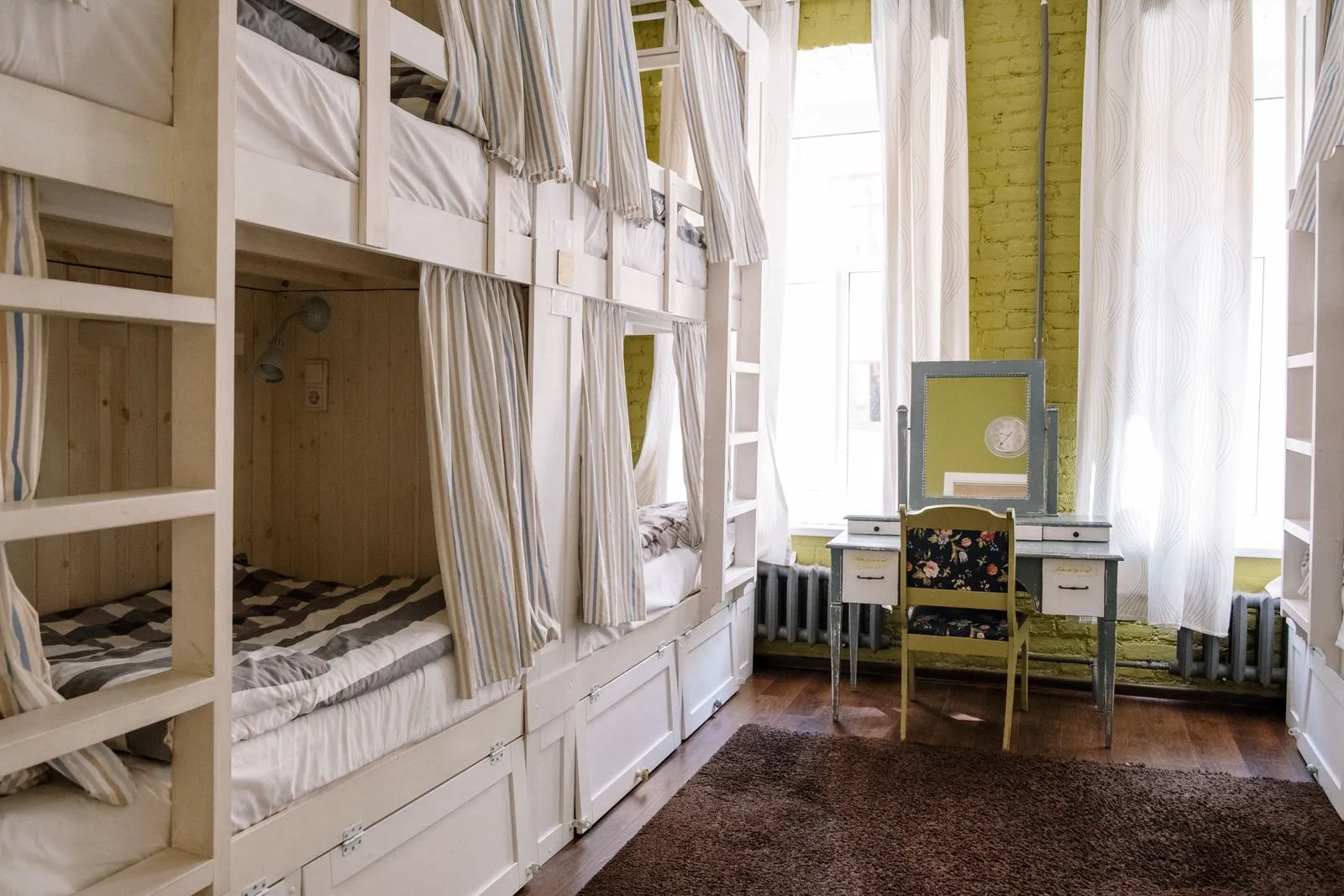 Cameră de hostel cu paturi supraetajate și perdele pentru intimitate