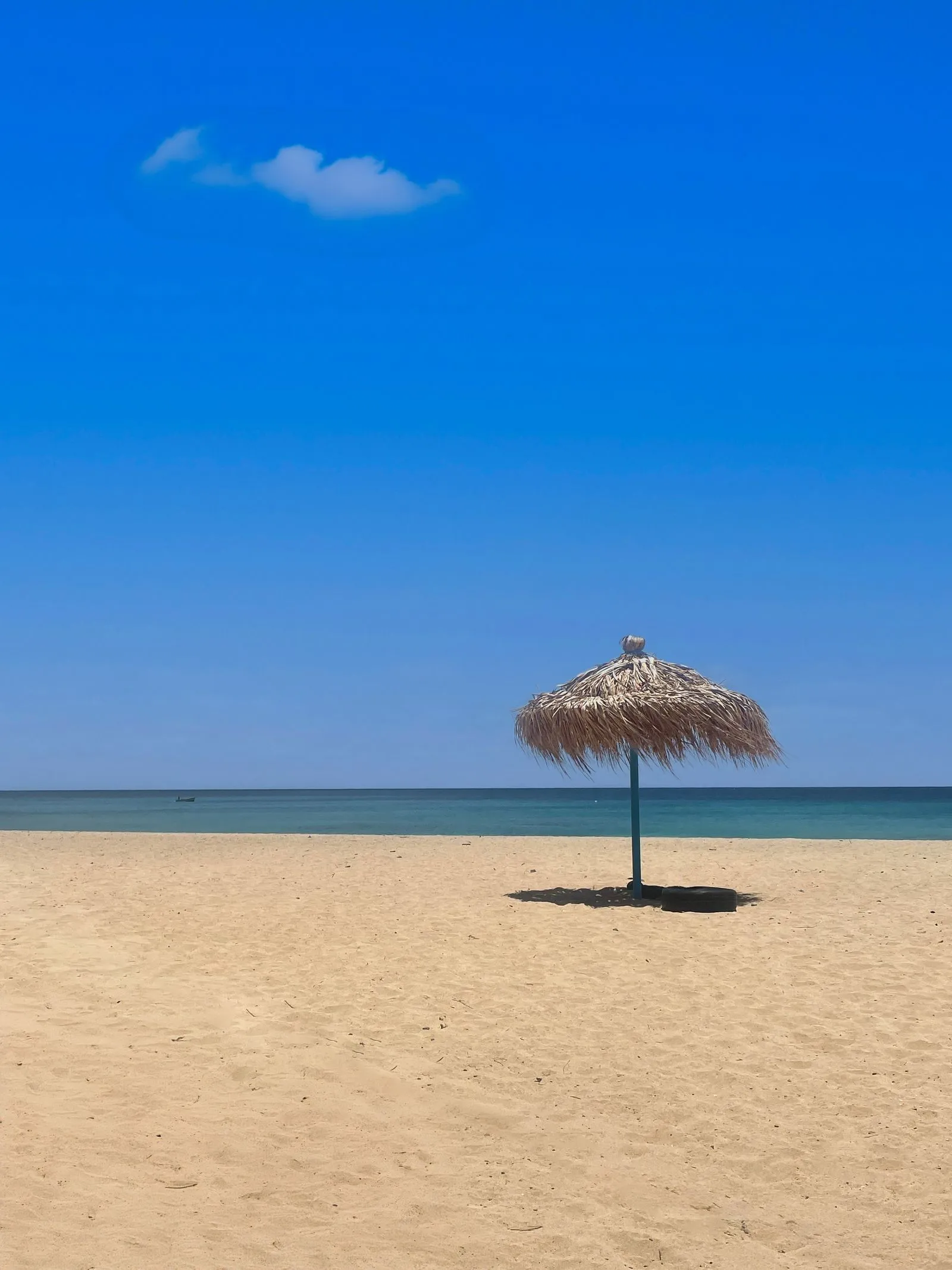 Plajă cu nisip deschis și umbrelă de paie la Santa Maria, pe insula Sal din Capul Verde