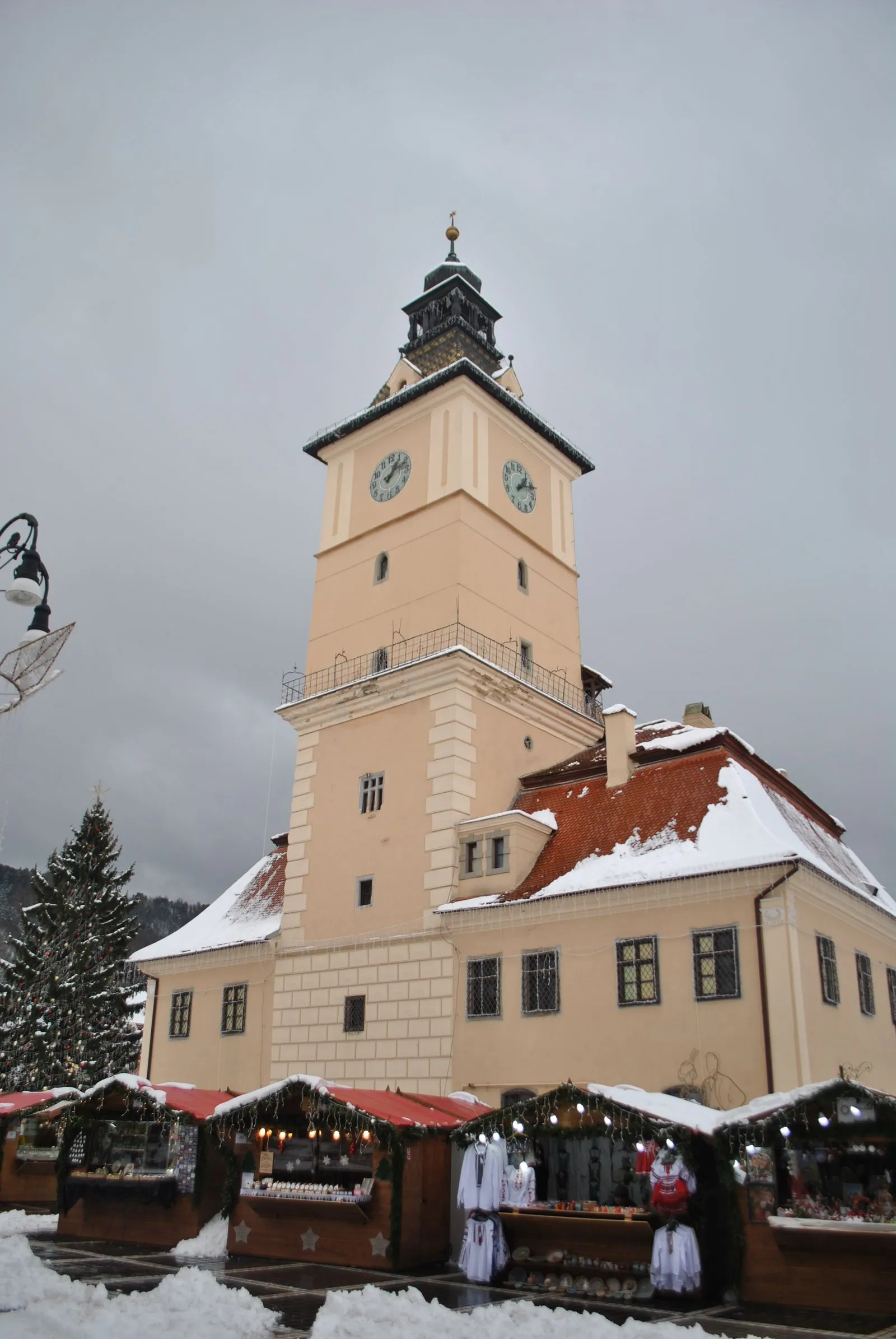Turnul cu ceas al Casei Sfatului din Brașov iarna, cu tarabele târgului de Crăciun