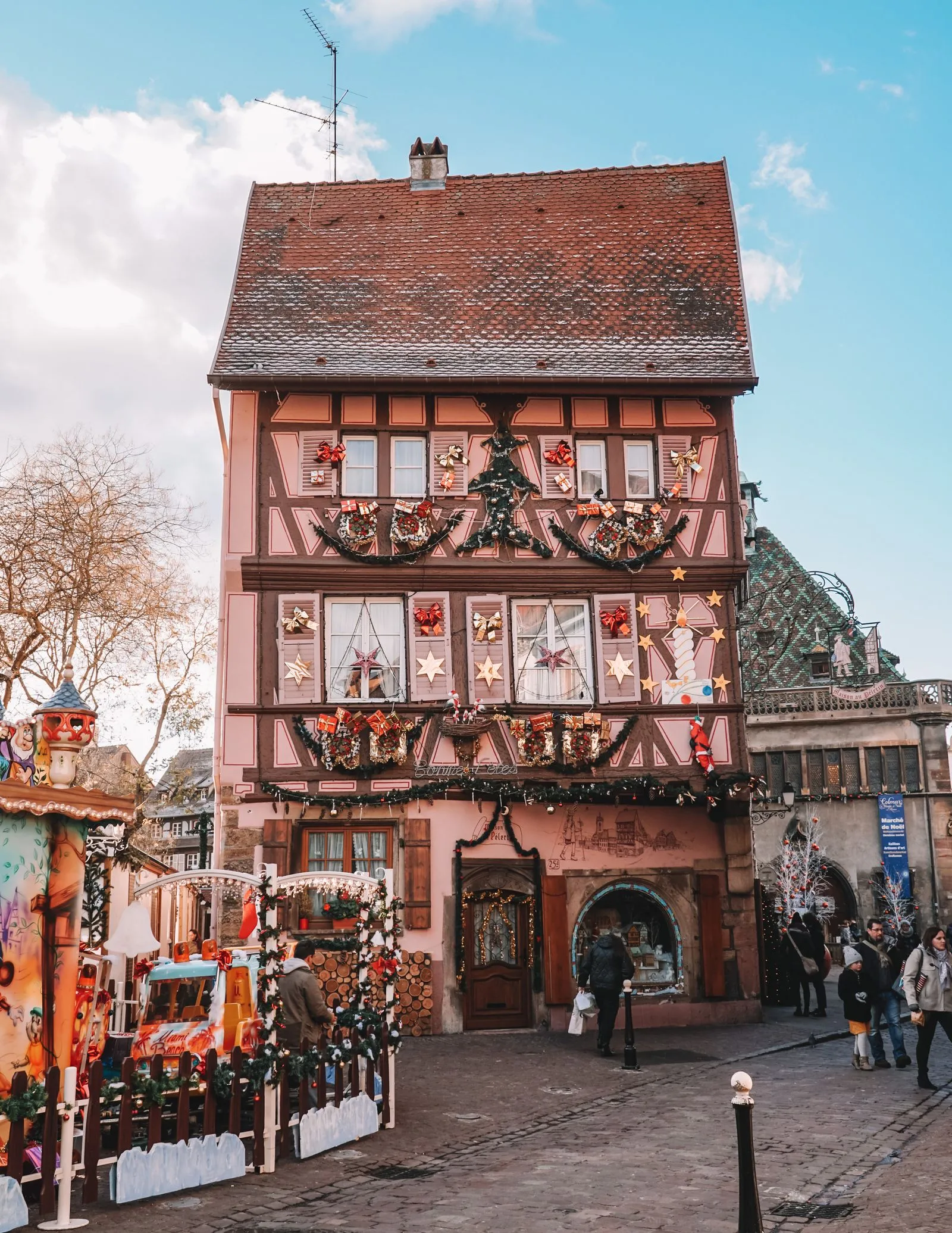 Casă cu grinzi decorată de Crăciun lângă o piață de târg din Colmar