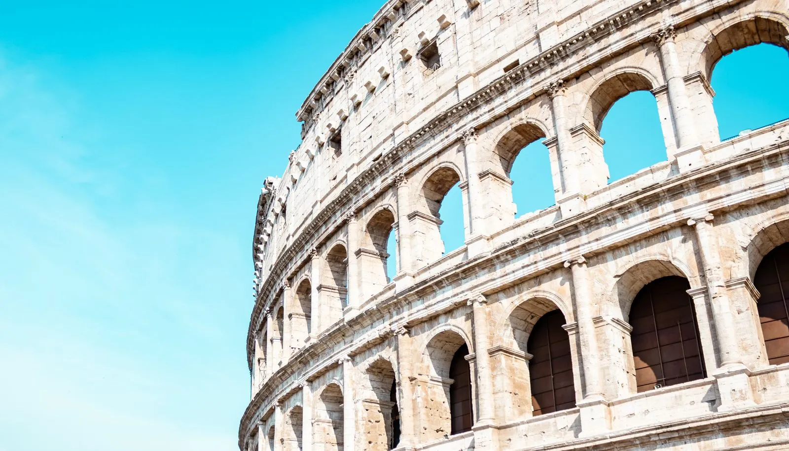 Colosseumul din Roma, arcadele de travertin în soare, sub cer senin