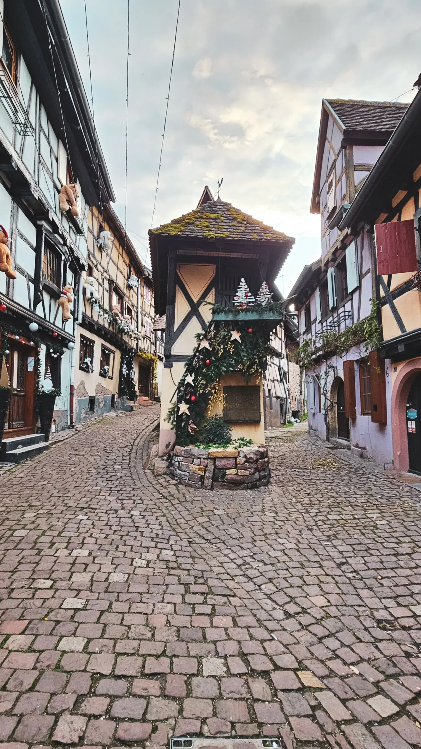 Stradă pavată cu case cu grinzi și decor de Crăciun în Eguisheim, Alsacia
