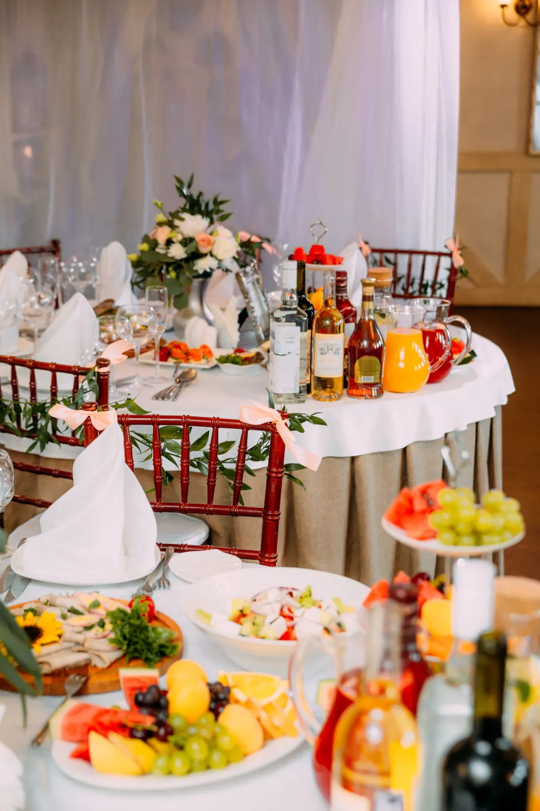 Masă rotundă aranjată pentru botez într-un restaurant, cu flori, fructe și băuturi