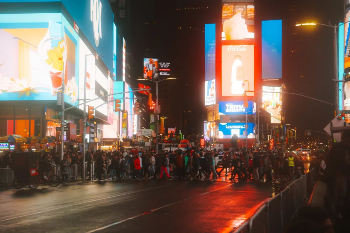 Times Square din New York noaptea, cu panouri luminoase și mulțime pe stradă