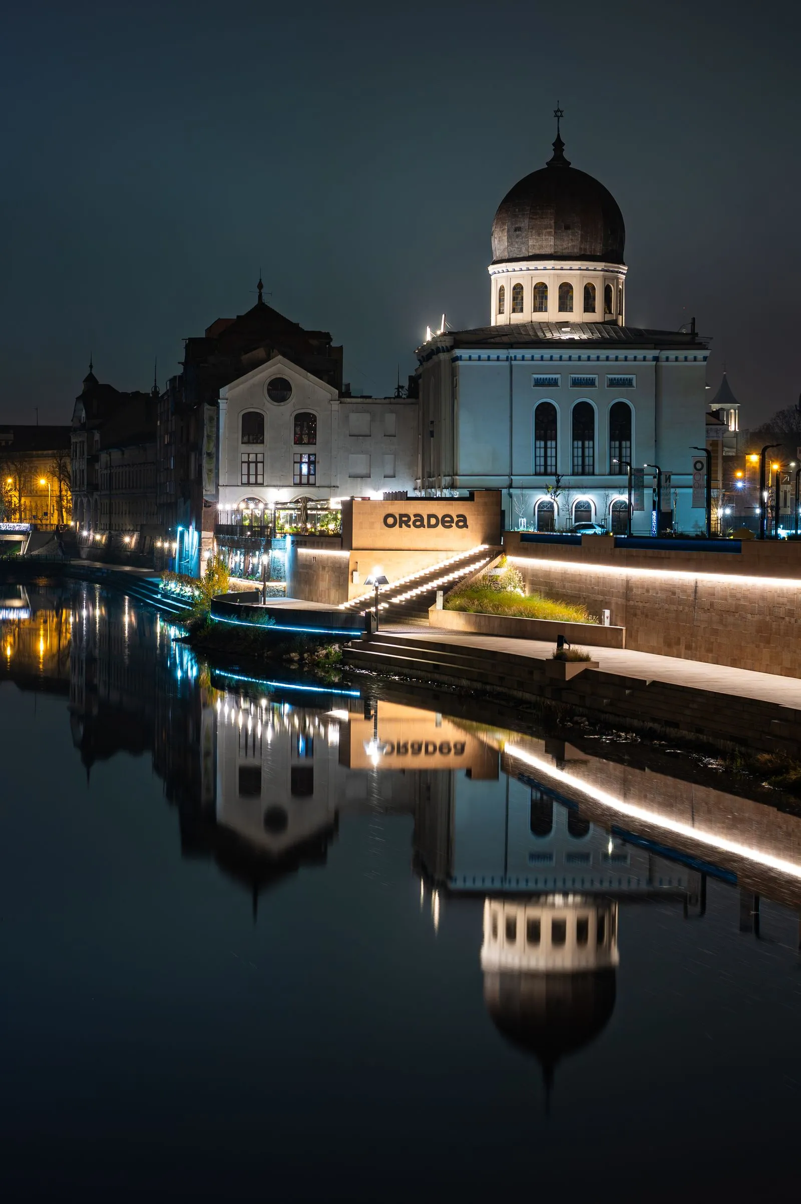 Sinagoga Sion și malul Crișului Repede din Oradea noaptea, cu reflexia clădirilor în apă