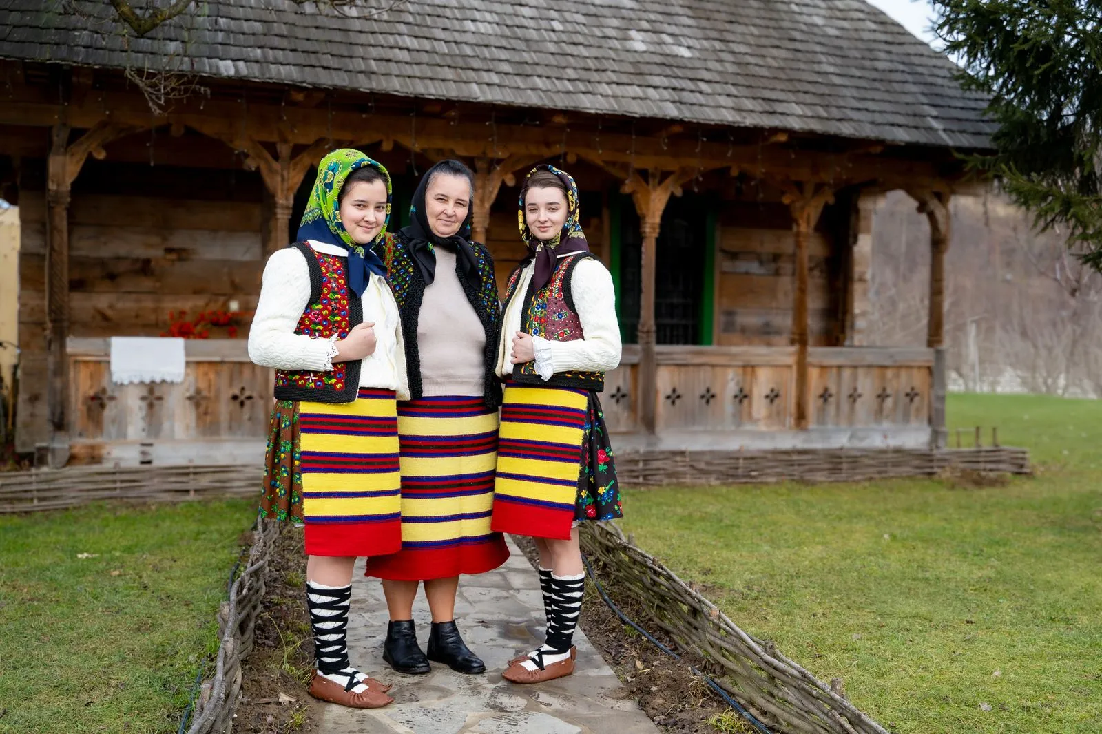 Trei femei în port popular maramureșean în fața unei case de lemn