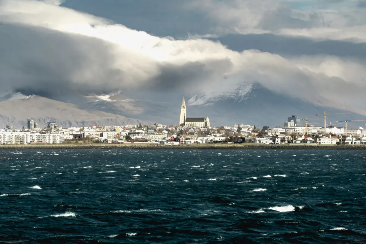 Panorama Reykjavik văzută de peste golf, cu biserica Hallgrímskirkja și munții acoperiți de nori