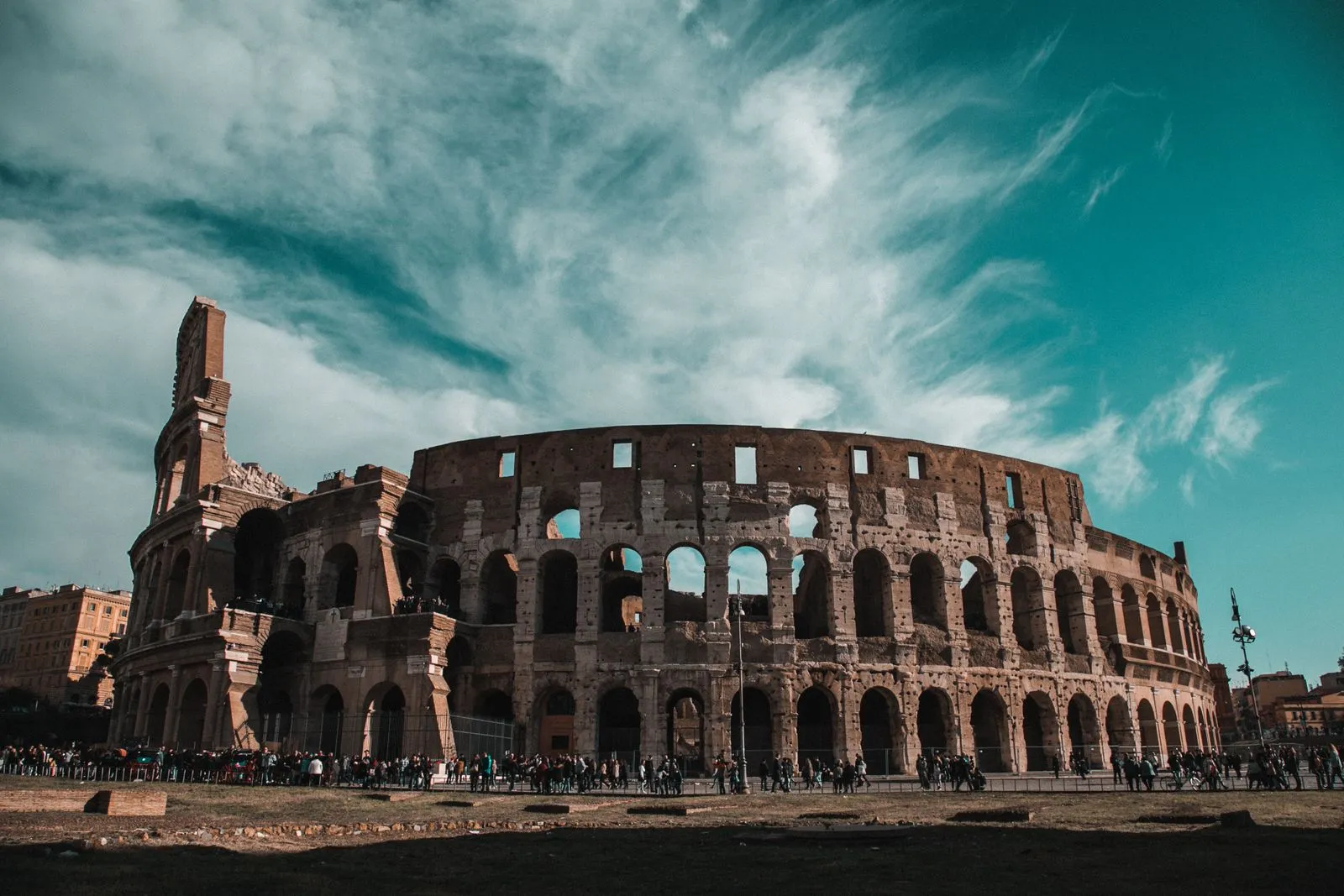 Colosseumul din Roma sub cer senin, cu turiști în fața arcadelor