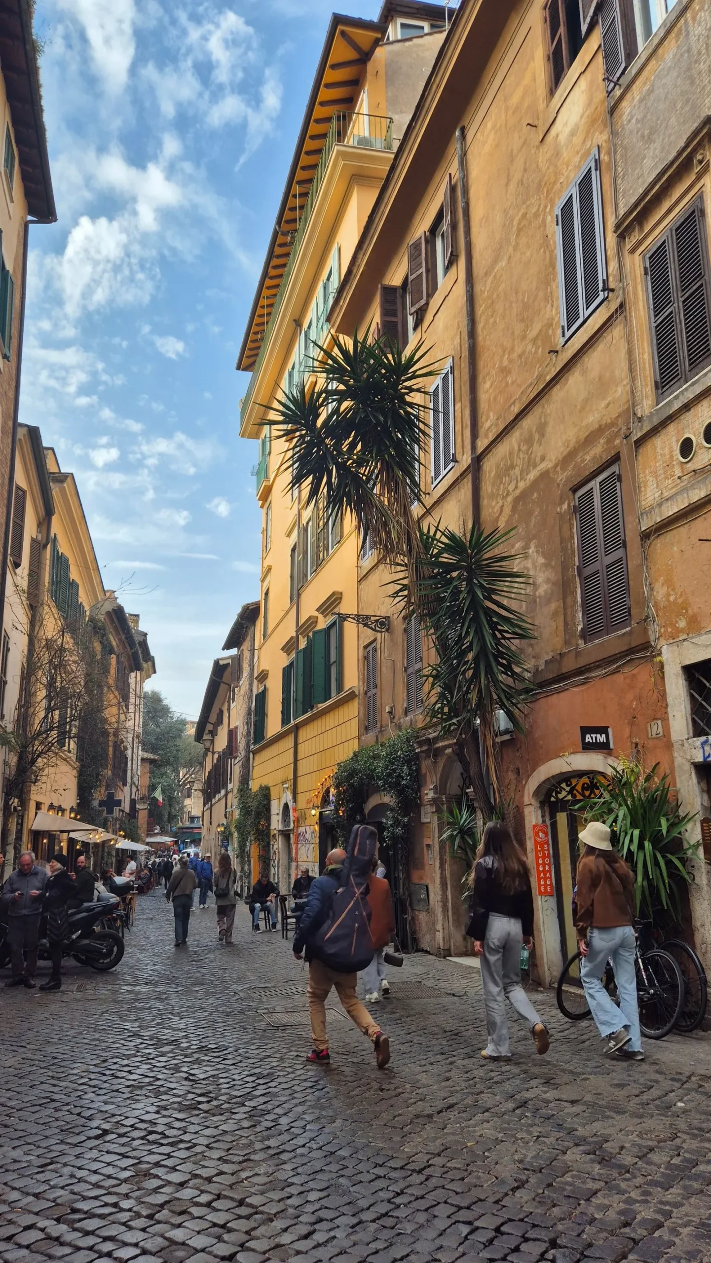 Stradă pavată cu clădiri ocru în cartierul Trastevere din Roma