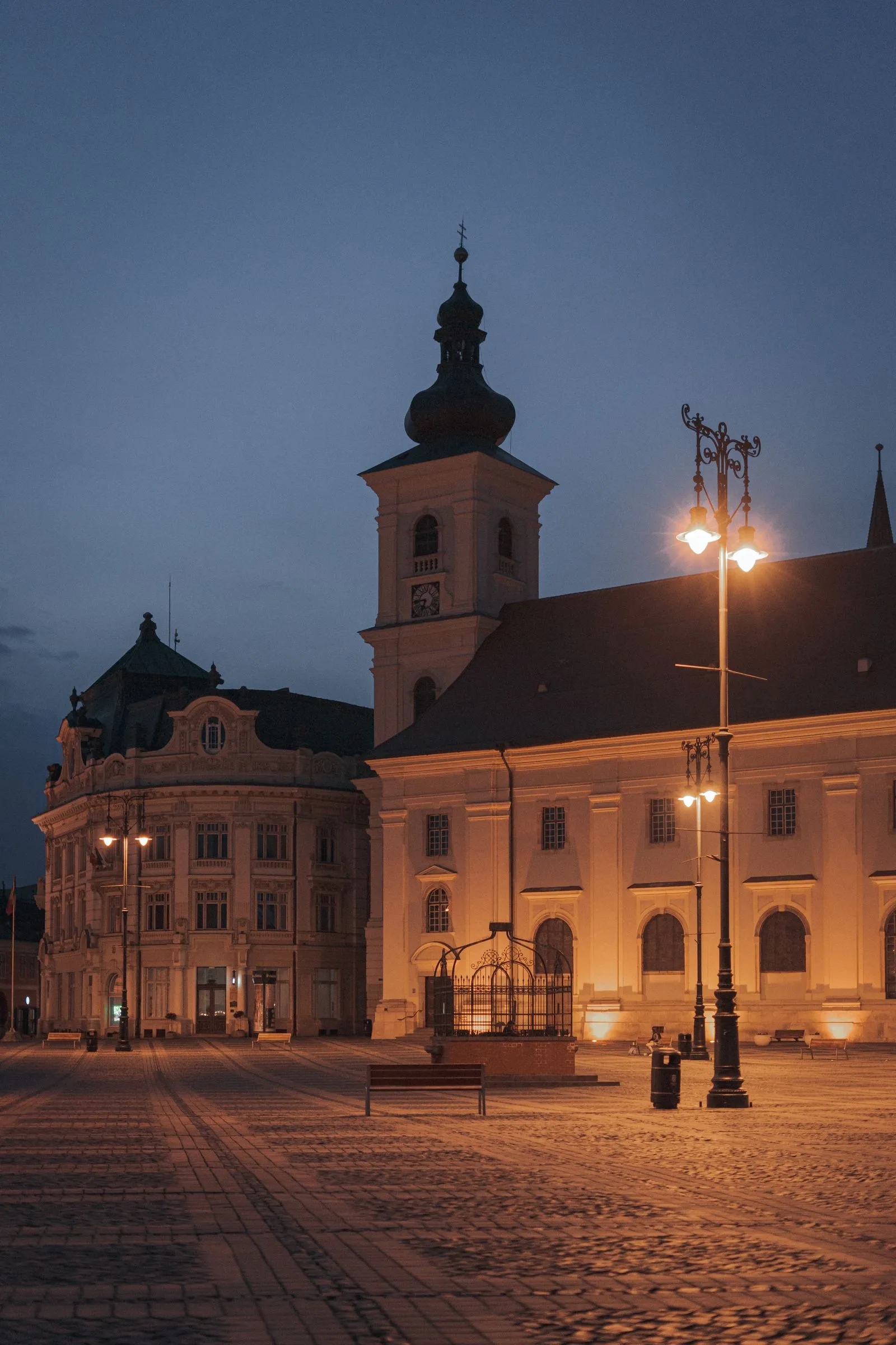 Piața Mare din Sibiu seara, cu Biserica Romano-Catolică și Palatul Primăriei luminate