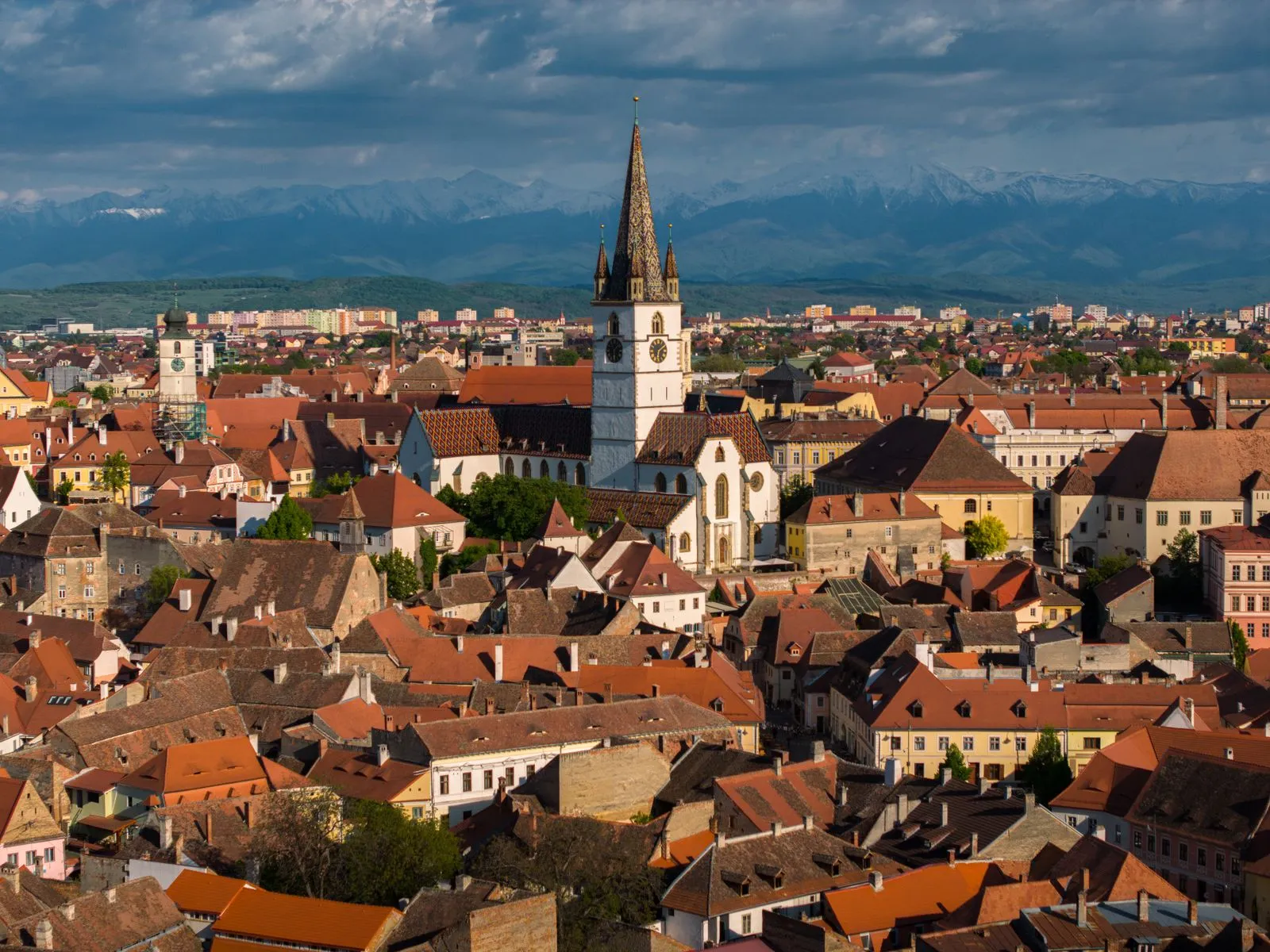 Panorama centrului vechi din Sibiu, cu turnul Catedralei Evanghelice și munții Făgăraș în fundal