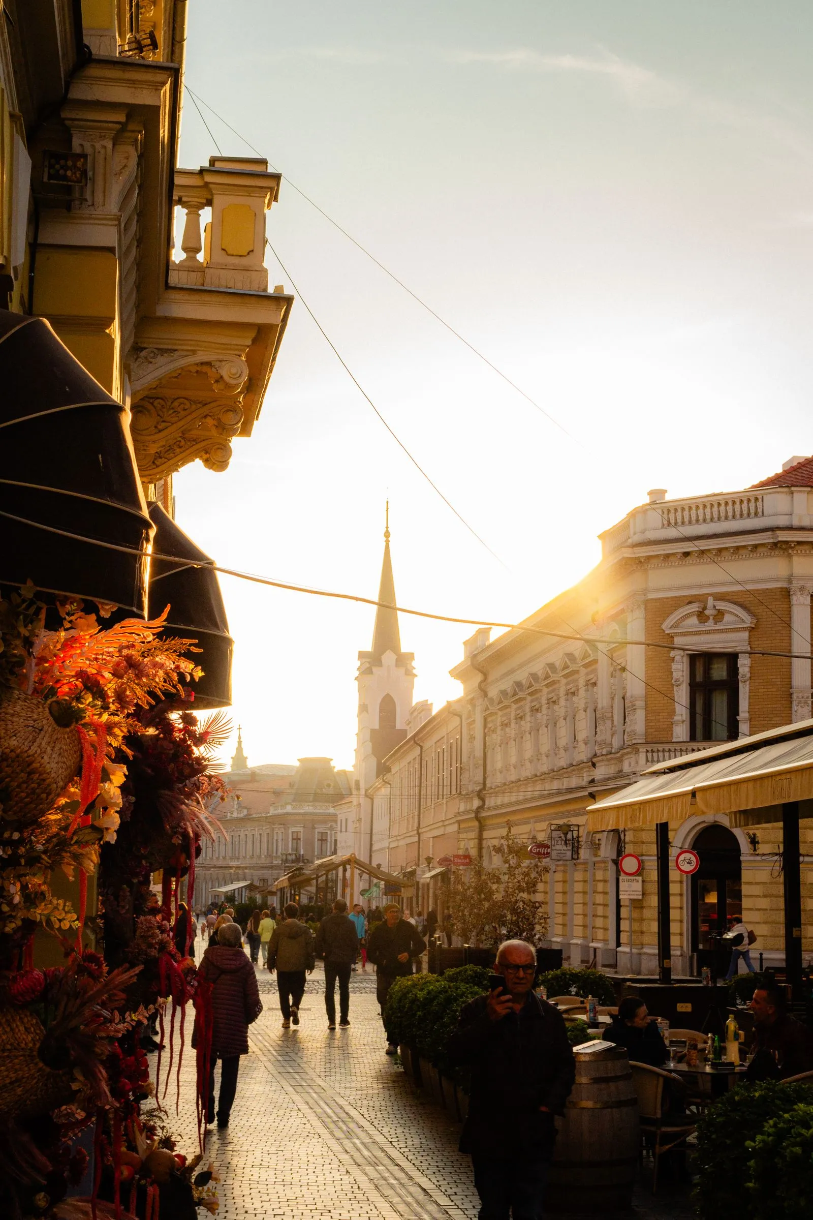 Stradă pietonală cu terase și clădiri istorice în centrul Oradiei, la apus
