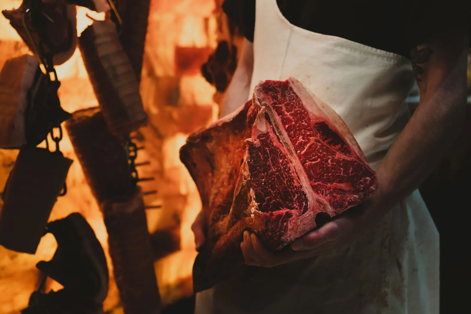 Măcelar care ține o bucată de T-bone crud într-o cameră de maturare a cărnii de vită