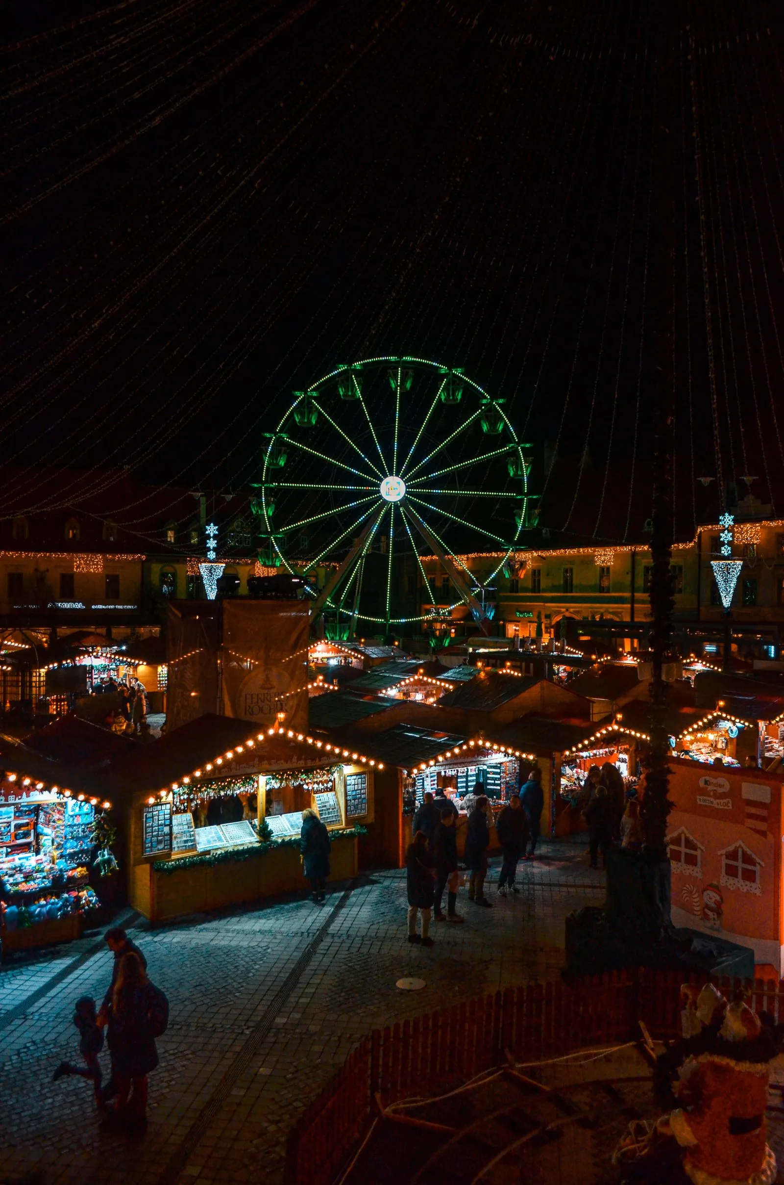 Târgul de Crăciun din Piața Mare, Sibiu, noaptea, cu roata panoramică și căsuțele luminate