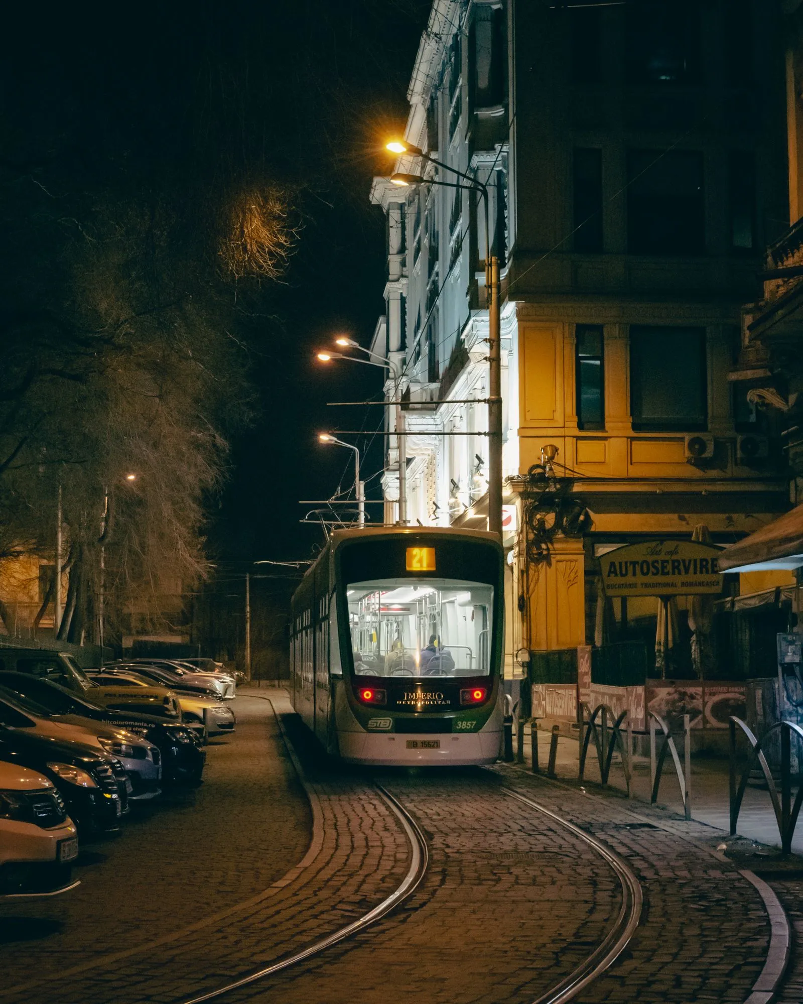 Tramvai pe o stradă din București noaptea, cu clădiri vechi luminate