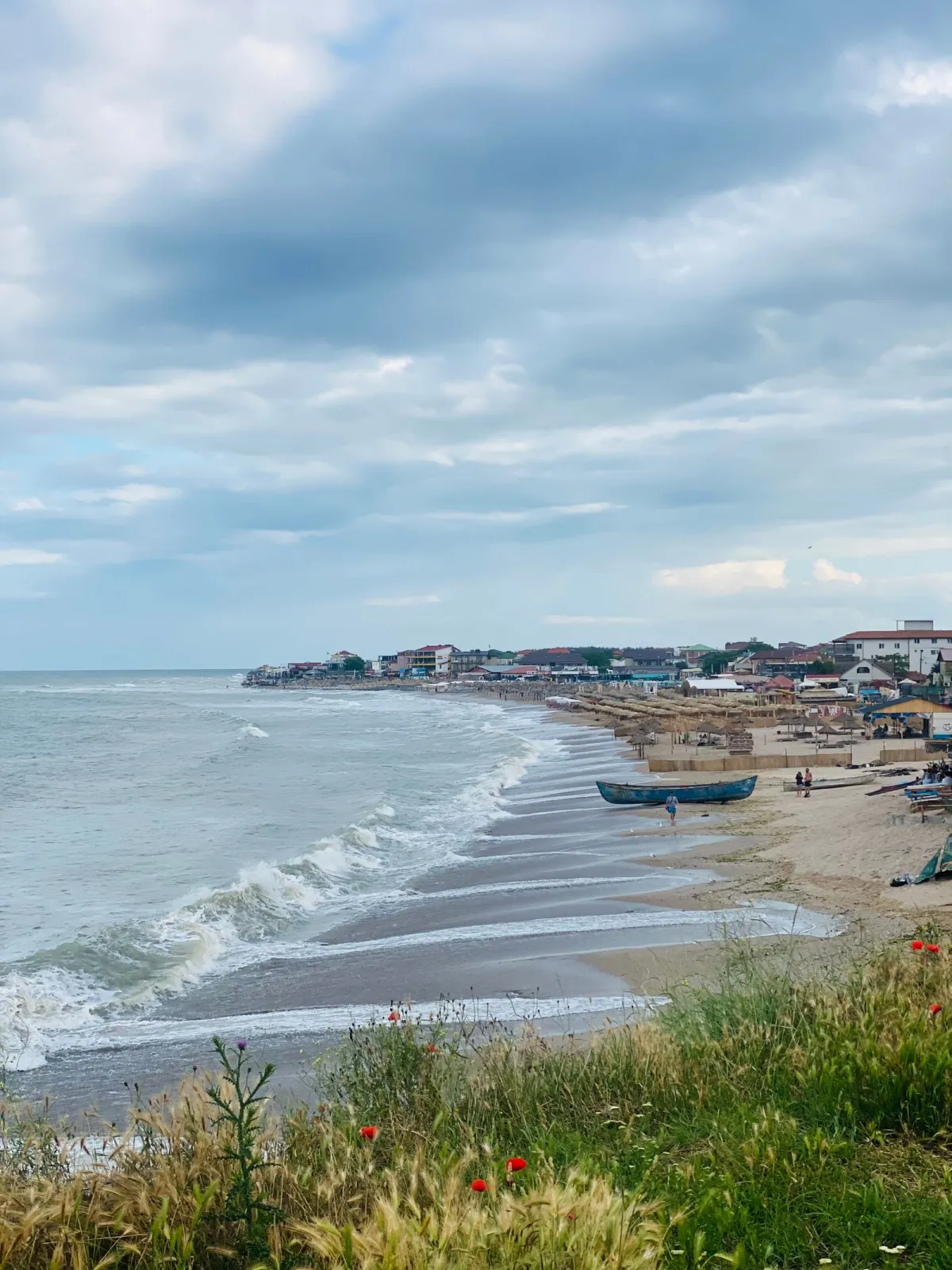 Plaja din Vama Veche, cu umbrele de stuf și bărci pescărești pe nisip