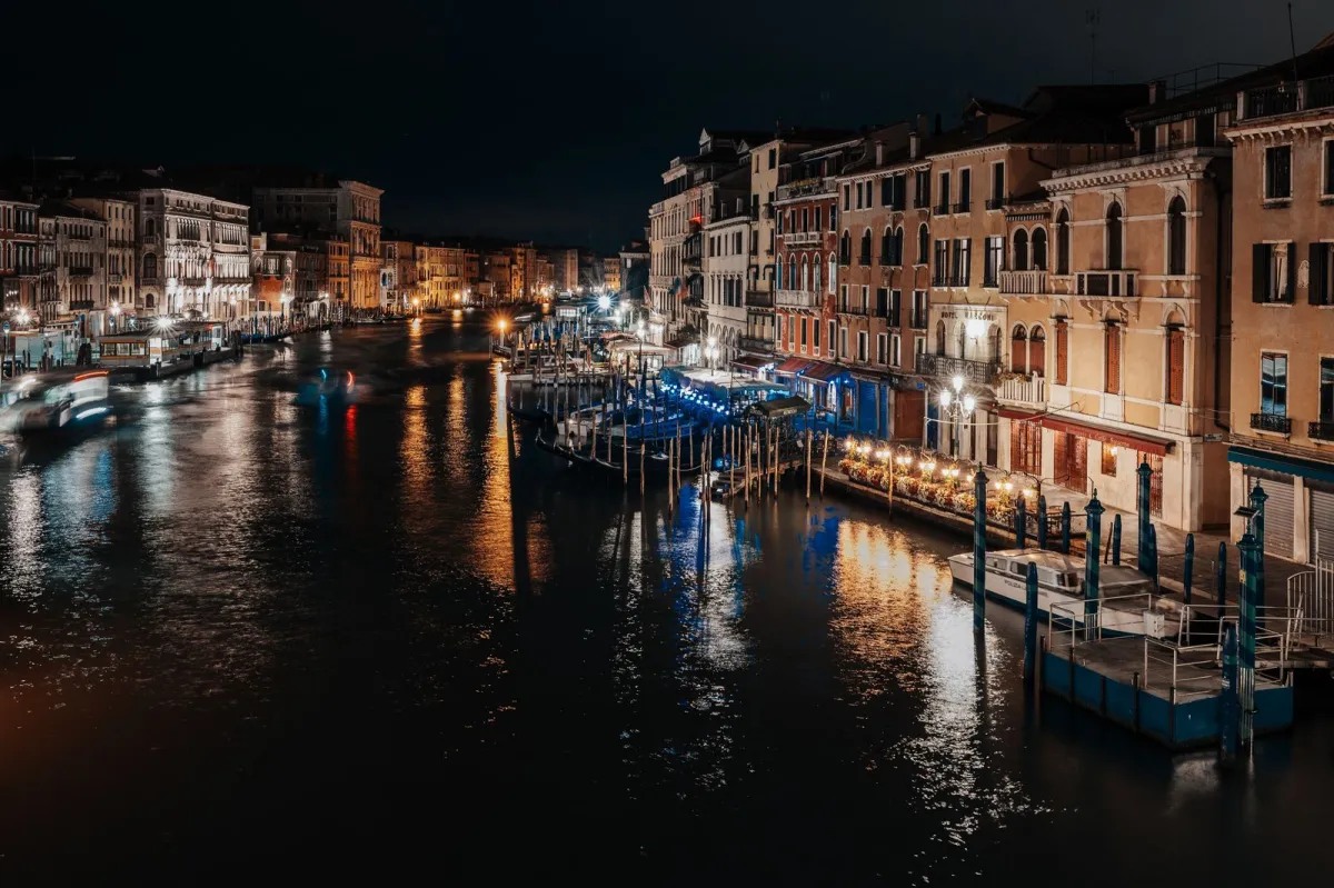 Canal Grande din Veneția noaptea, cu palate luminate și gondole la mal