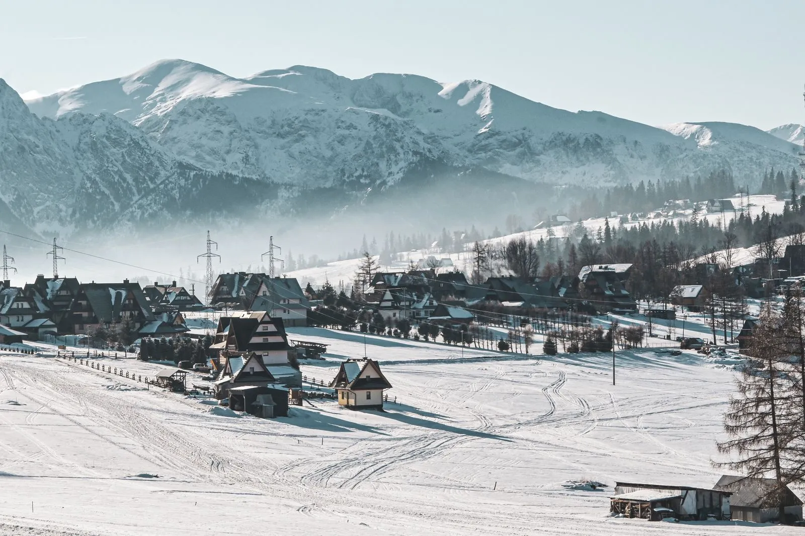 Case de lemn acoperite de zăpadă la marginea orașului Zakopane, cu Munții Tatra în fundal