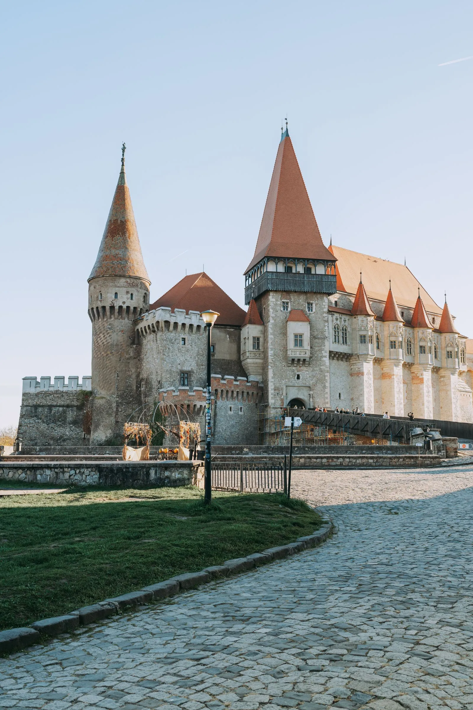 Aleea pavată care duce spre castelul din Hunedoara, cu turnurile și acoperișurile roșii