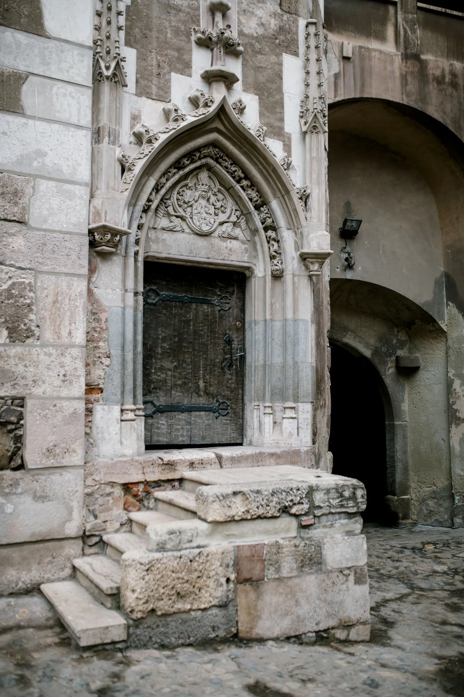 Portal gotic cu ușă veche de lemn în curtea interioară a castelului Corvinilor