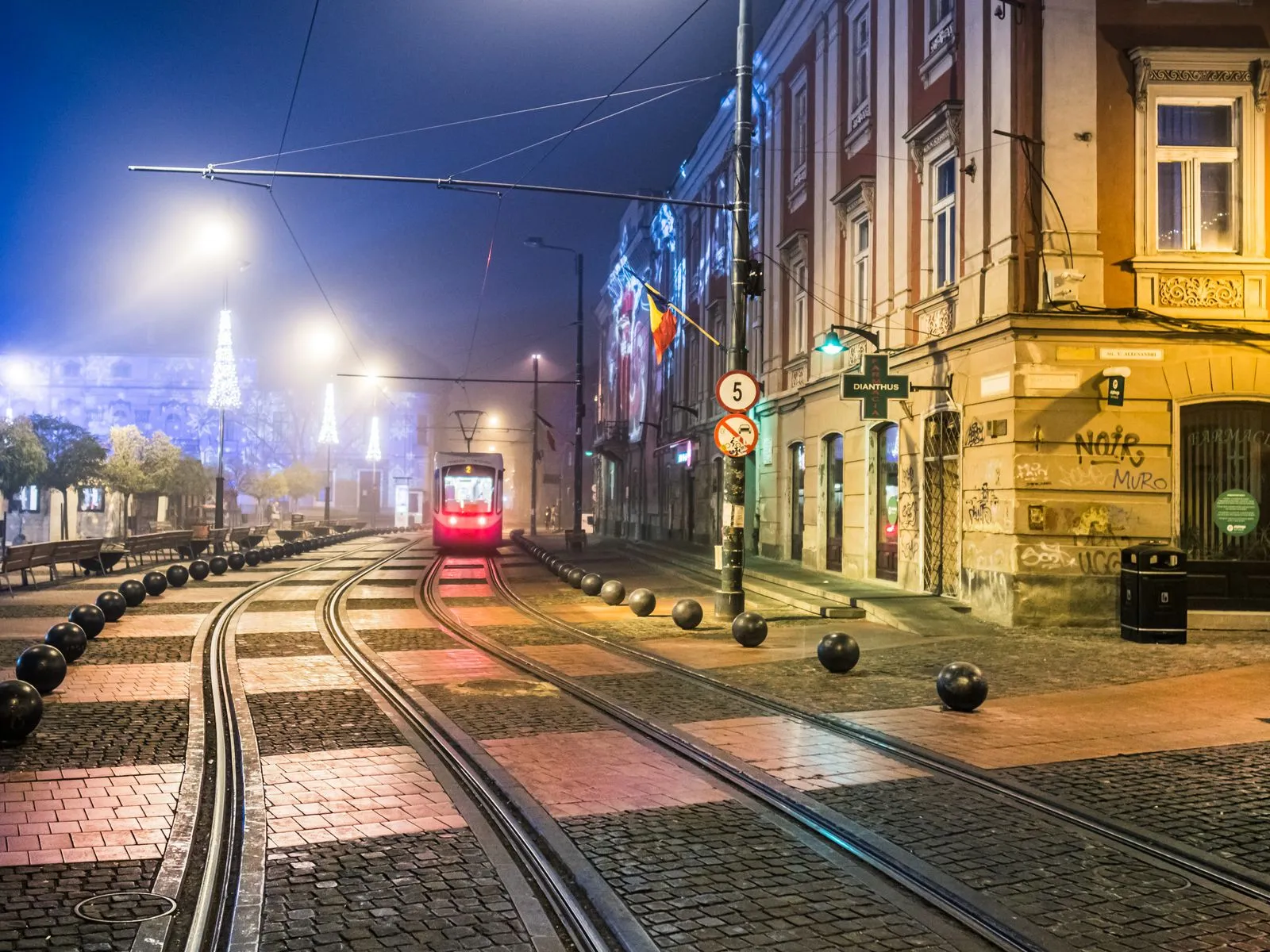 Tramvai în centrul Timișoarei, seara, cu instalațiile de lumini de sărbători din zona Pieței Victoriei